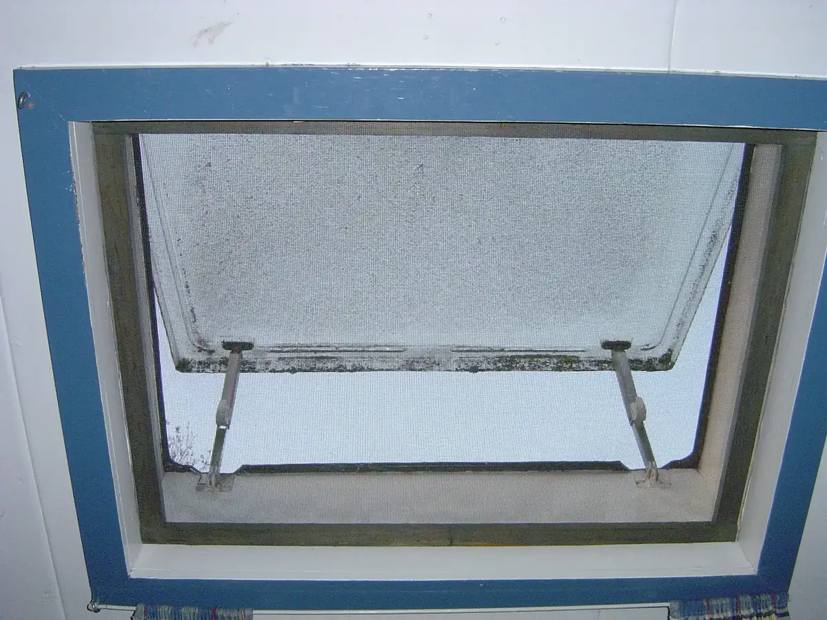 a propped-open window fitted with a mesh insect screen